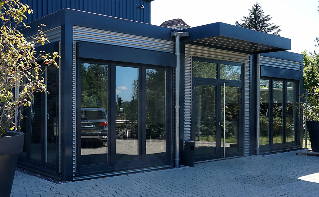 Moderne Containeranlage mit großer Fensterfront, Materialmix aus lakietem Stahl und gestaltetem Aluminium