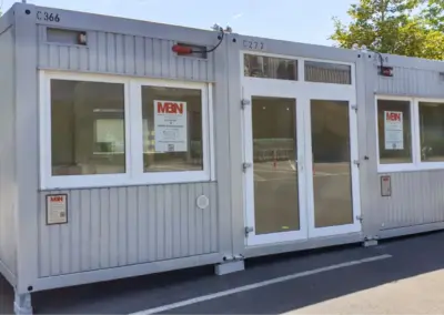 Modulare Verkaufscontainer-Anlage mit Türen und Fenstern, geeignet als temporärer Shop oder Verkaufsfläche.